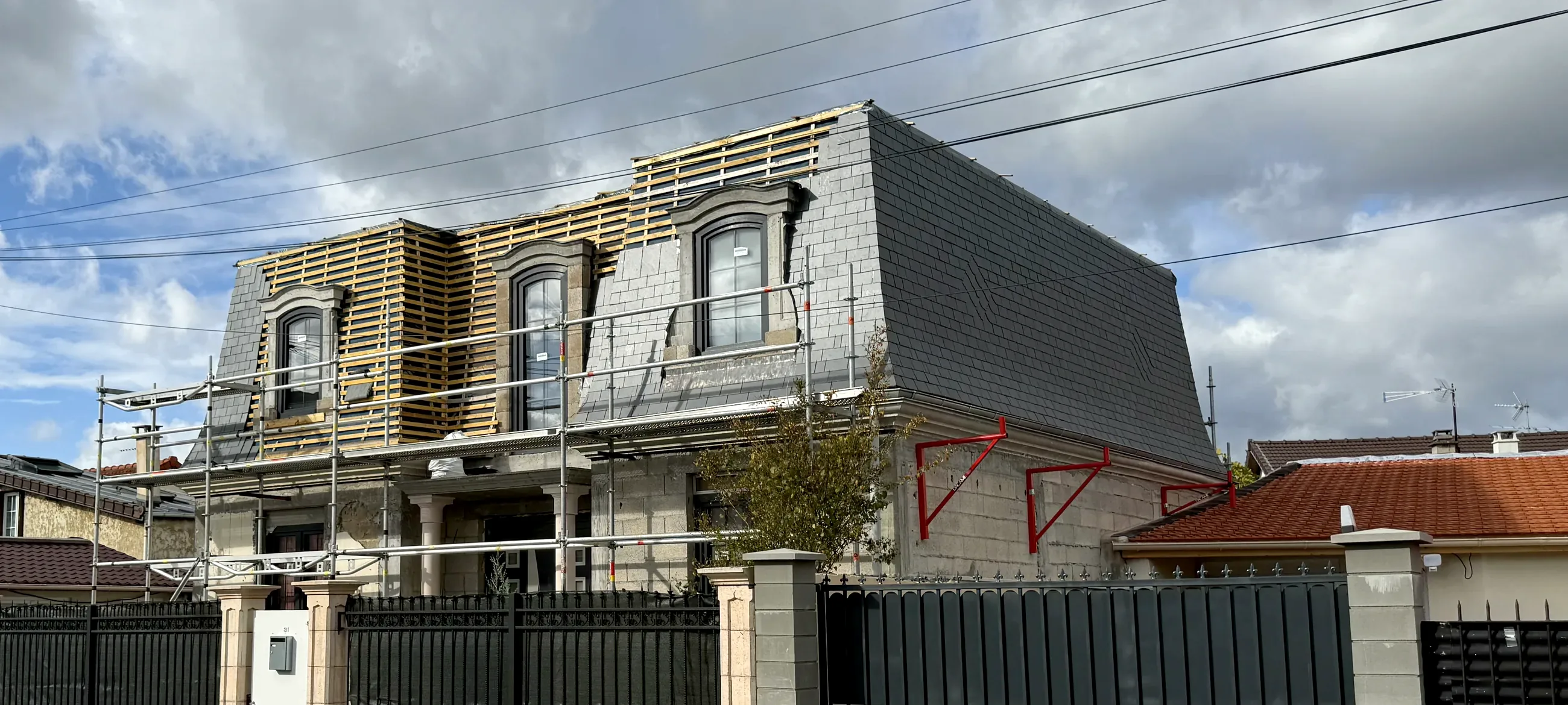 Toiture mansardée en ardoise en cours de réfection par Will Couvreur : lucarnes reprises une à une, liteaunage neuf et échafaudage de pied monté sur rue